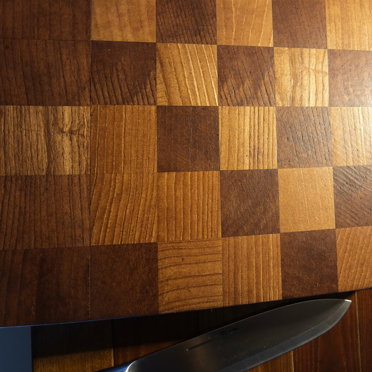Surface d'une planche en bois de bout vue de dessus, damier de blocs clairs et foncés, couteau posé au bord Image